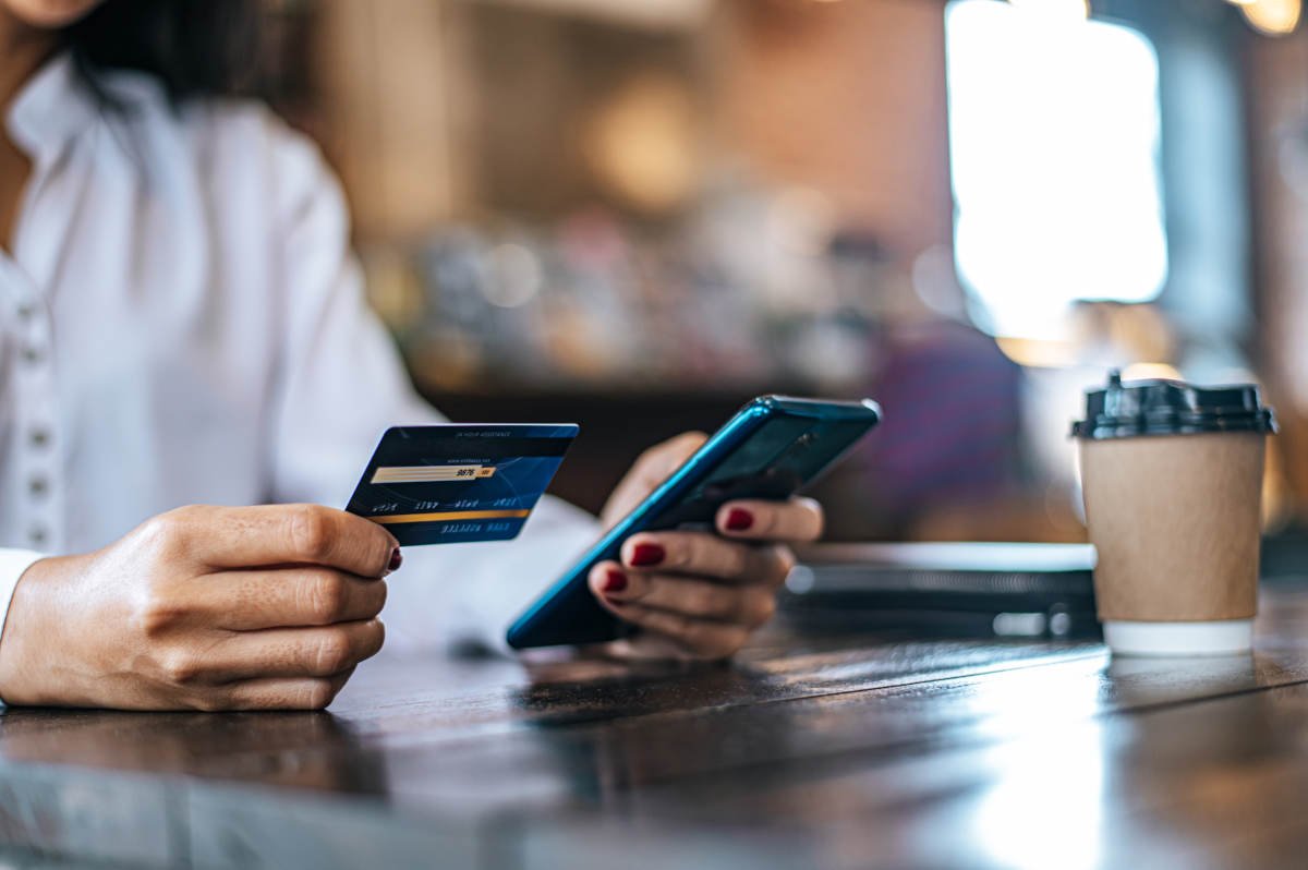Pessoa pagando com cartão de débito em uma página de checkout acessada por link de pagamento no celular.